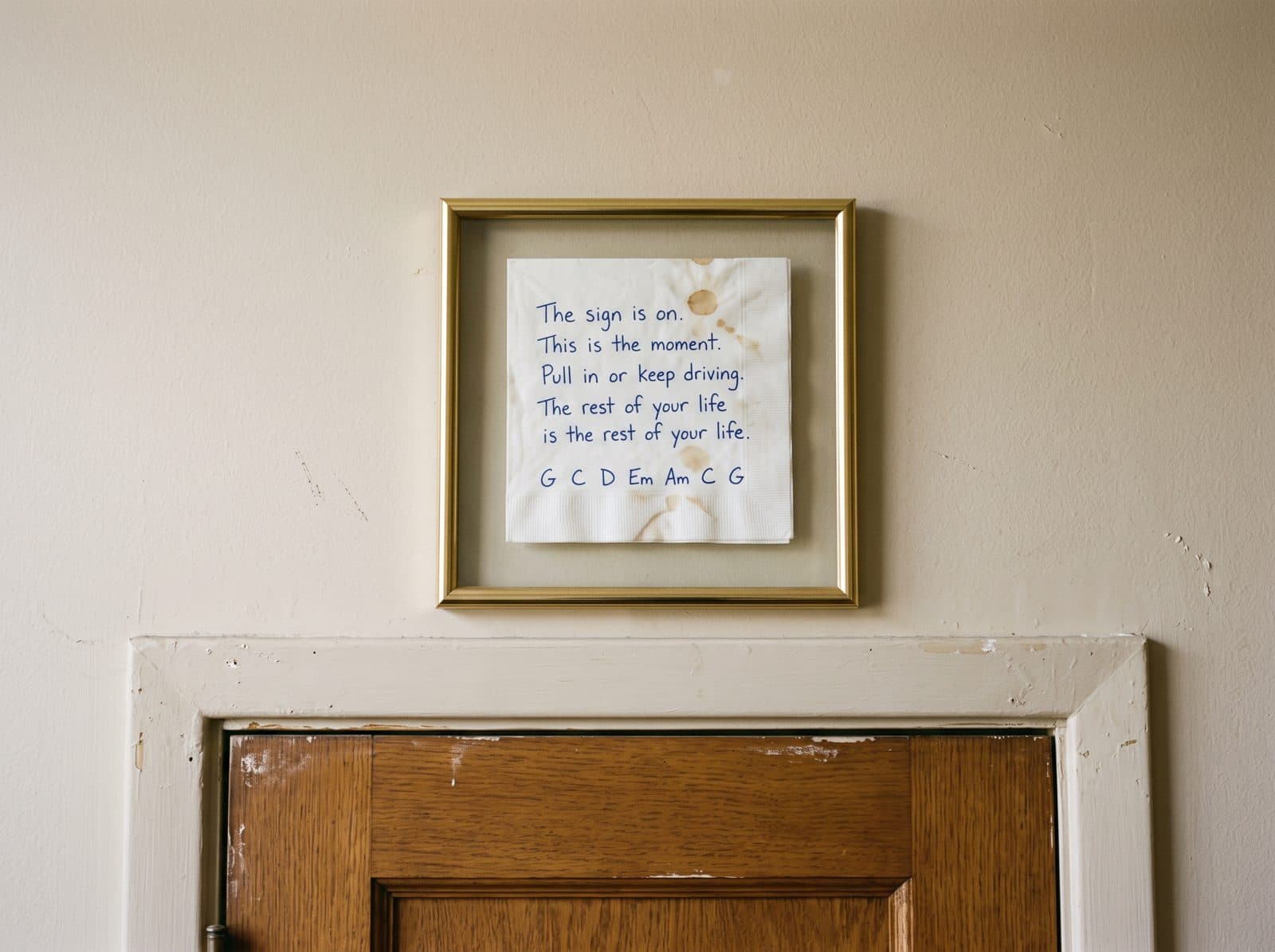 A framed handwritten napkin above an office door